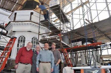 Steeple chase: Former interim First Parish minister and board member Richard Kellaway, board chairperson Julie Simmons, Rev. Art Lavoie and Rich Friberg, project manager and instructor for the North Bennet Street School are shown inside the temporary workshop on Parish Street, where restoration carpentry students are working to finish the two lantern sections of the historic church’s steeple. Photo by Bill Forry